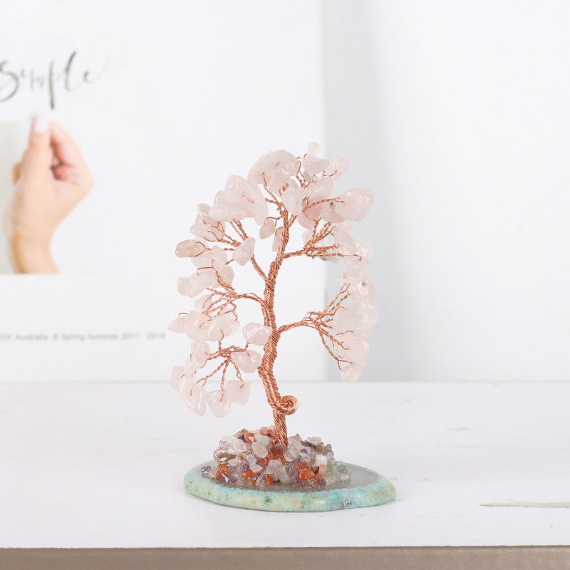 Arbre de Vie décoratif en pierres roses et fil de cuivre, monté sur une base en pierre naturelle avec des éclats de cristaux colorés.