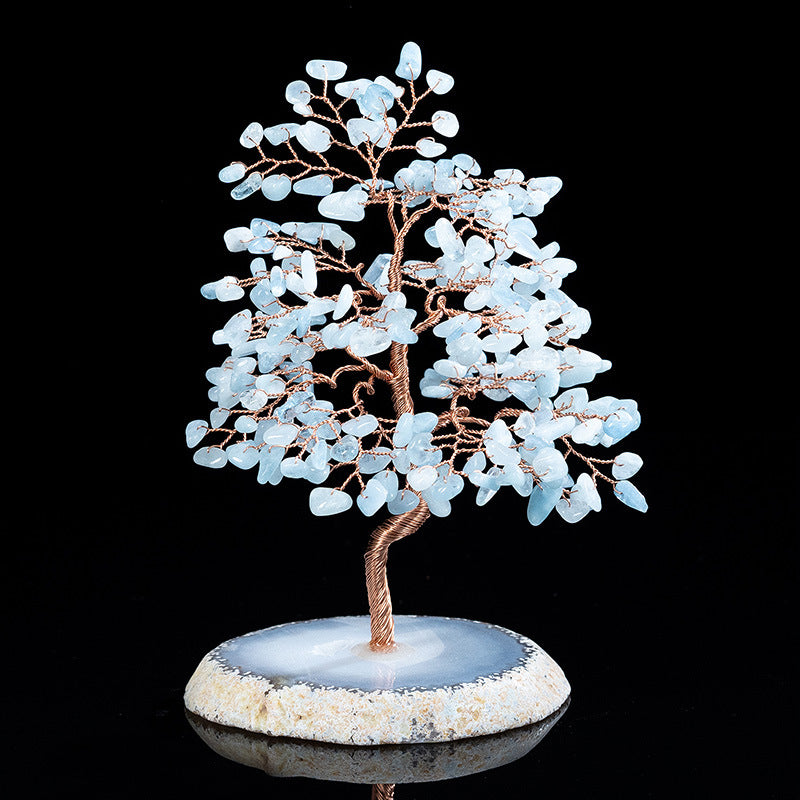 Arbre de Vie Sérénité, fait à la main avec des pierres d'aigue-marine bleues claires et du fil de cuivre, posé sur une base d'agate grise et blanche.