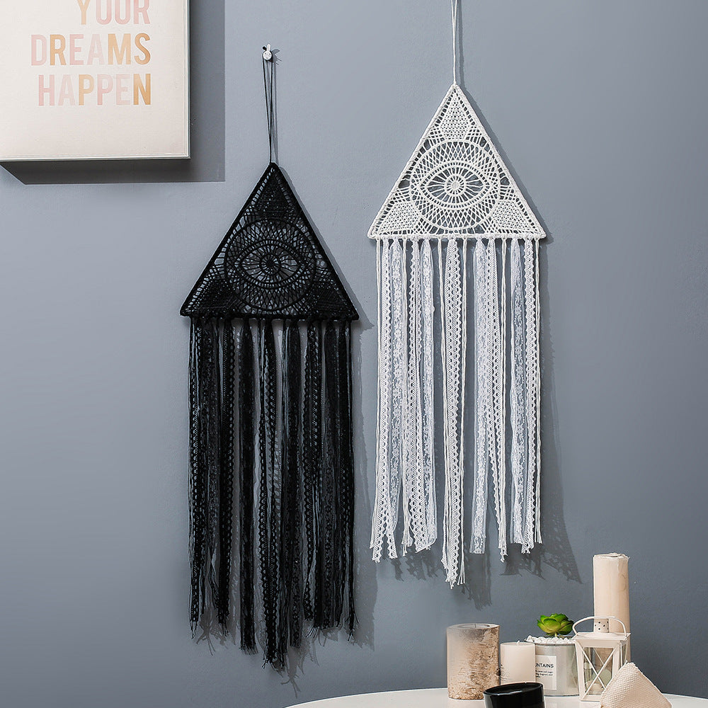 Deux attrape-rêves muraux en forme de triangle suspendus au mur, l'un noir et l'autre blanc, ornés de motifs de mauvais œil et de franges.