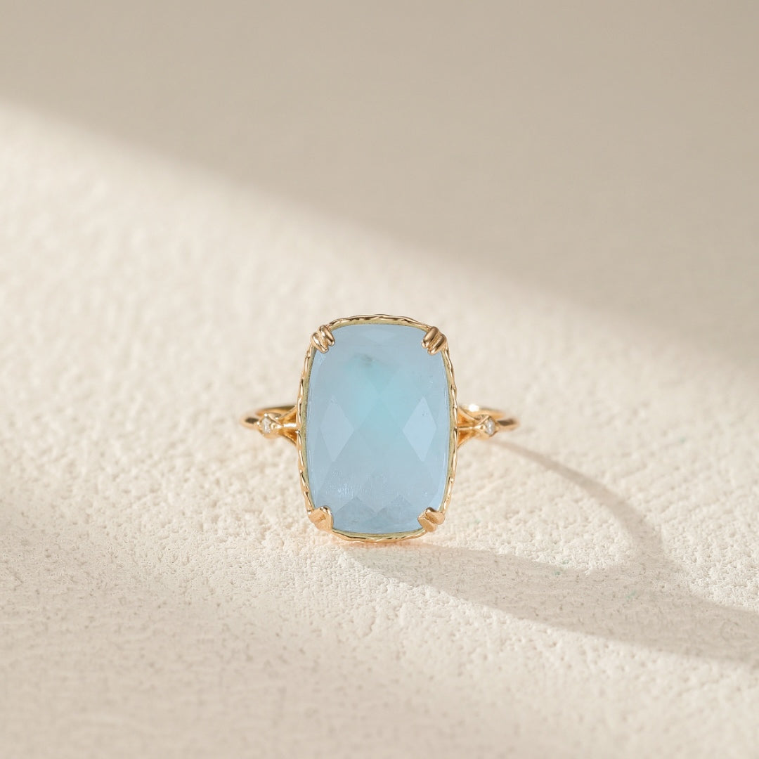 Bague aigue marine Sérénité Océane en argent plaqué or, avec pierre bleu ciel doux et monture dorée ondulée, disponible en tailles FR50-FR60, symbolisant protection et calme.