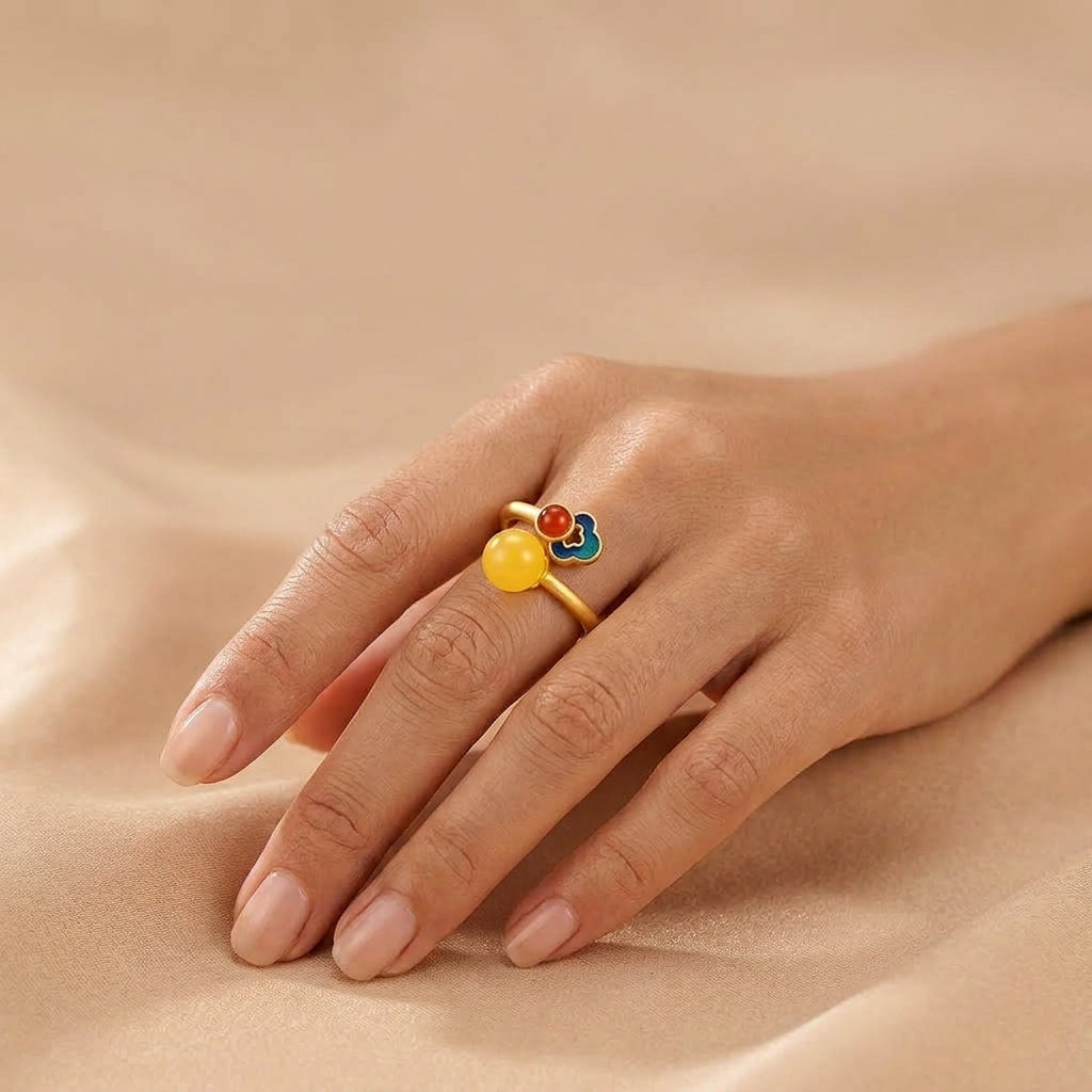Bague Nuage Précieux en argent plaqué or avec perle d'ambre jaune, pierre rouge et motif floral émaillé portée sur un doigt
