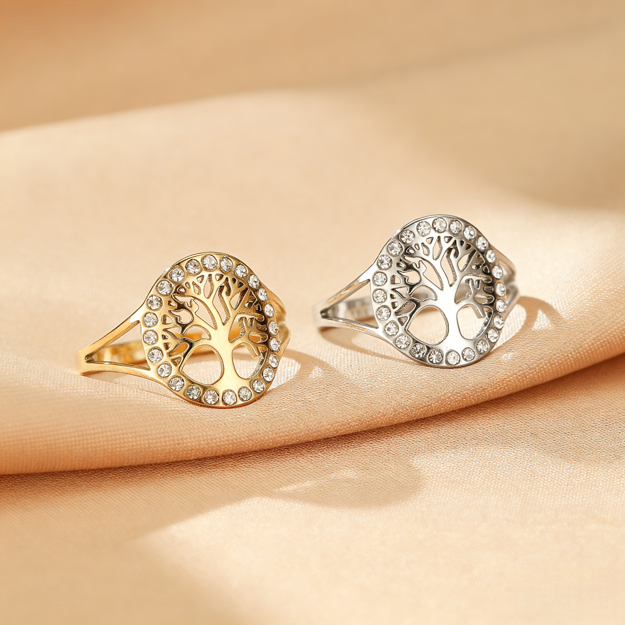 Bague Arbre de Vie lumineuse en argent et dorée, ornée de cristaux scintillants, sur fond satiné.