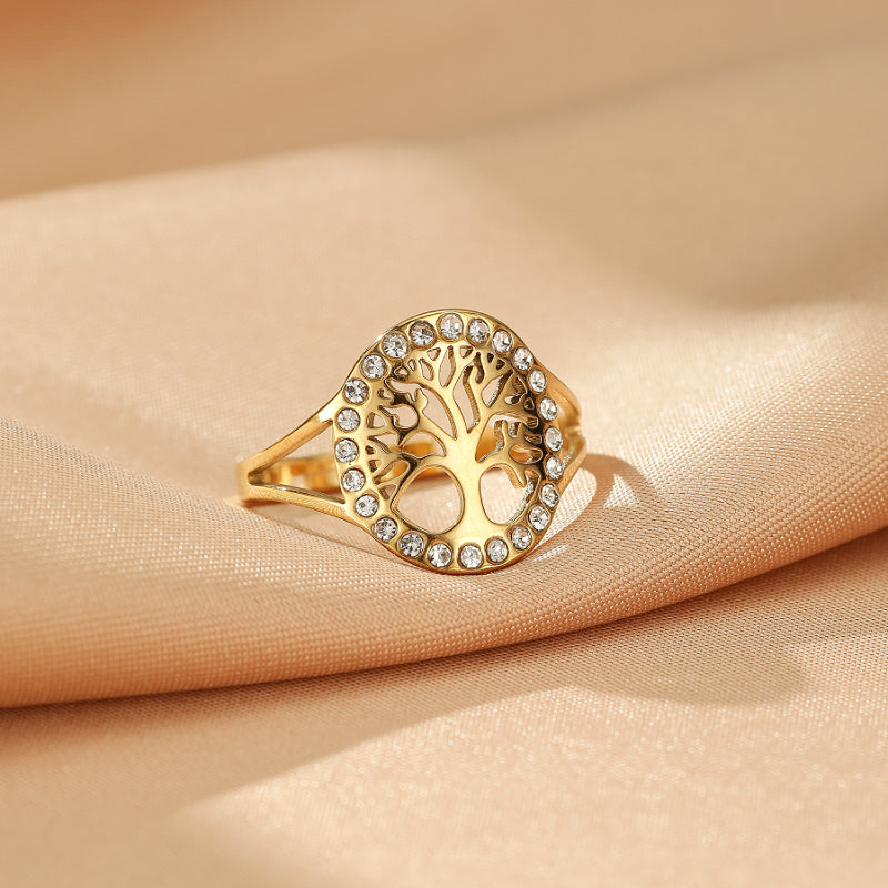 Bague Arbre de Vie dorée sertie de cristaux brillants, motif stylisé sur fond satiné.