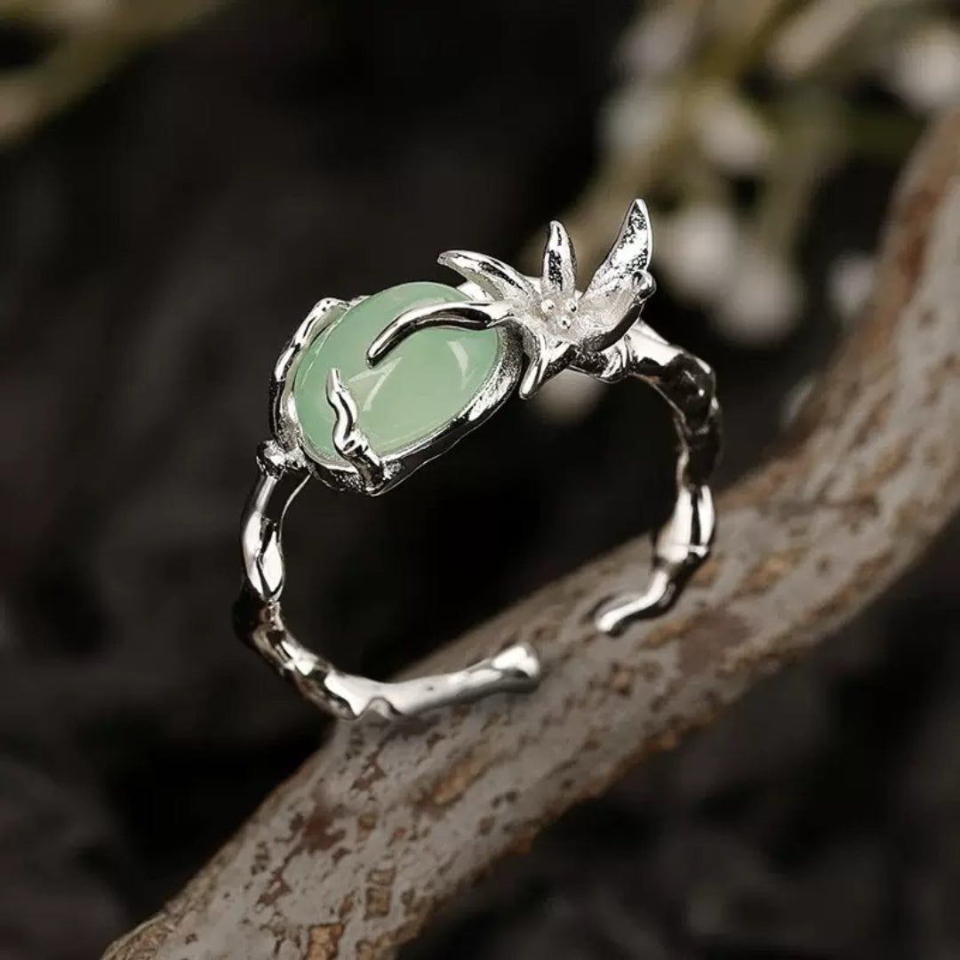 Bague avec une pierre d'aventurine verte ovale, sertie sur une monture en argent sculptée en forme de branche d'arbre avec des détails floraux.