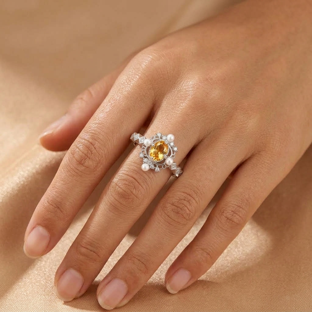 Bague Splendeur Dorée en argent ornée d'une citrine ovale centrale entourée de perles délicates portée sur un doigt