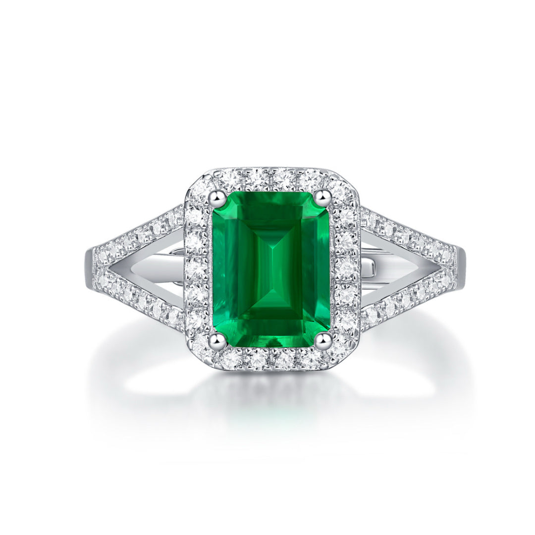 Bague en argent 925 sertie d'une émeraude taille émeraude entourée de petits diamants scintillants, design unique.