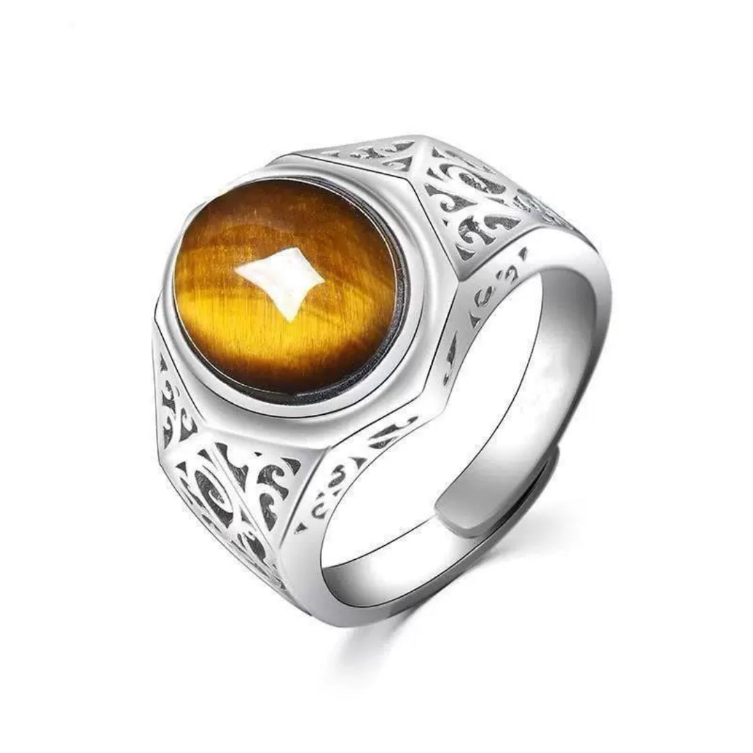 Bague pour homme avec une pierre d'œil de tigre ovale au centre, sertie sur un anneau argenté orné de motifs gravés et d'une finition polie.
