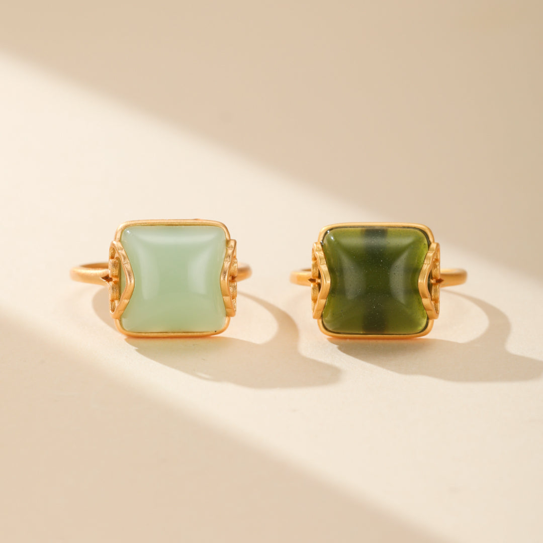 Bague 'Essence d'Abondance' en plaqué or, ornée d'un jade vert clair carré et de nuages dorés, symboles de bonheur. Ce bijou raffiné et unique est une fusion d'or scintillant et de sérénité. Parfaite pour un cadeau mémorable.