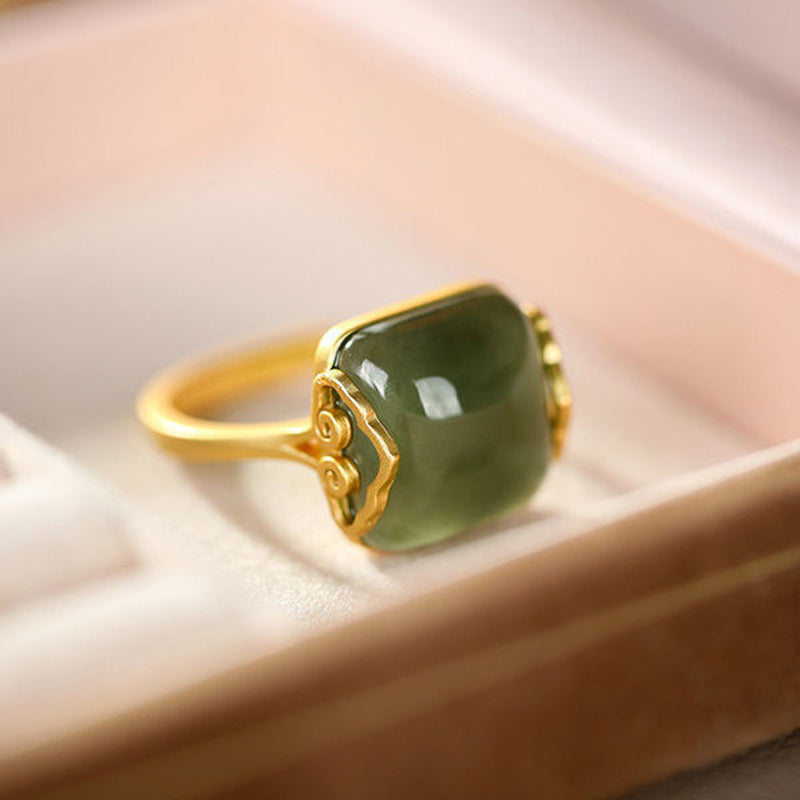 Bague en plaqué or avec une pierre de jade verte rectangulaire sertie sur un anneau doré aux motifs délicats.