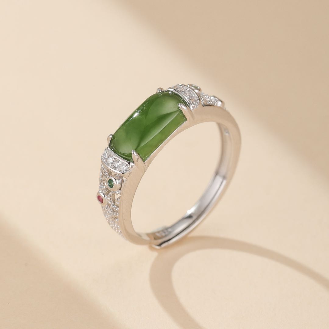 Bague élégante en argent plaqué or sertie d'une pierre de jade rectangulaire vert vif, entourée de petits zircons et de pierres rouges et vertes sur les côtés.
