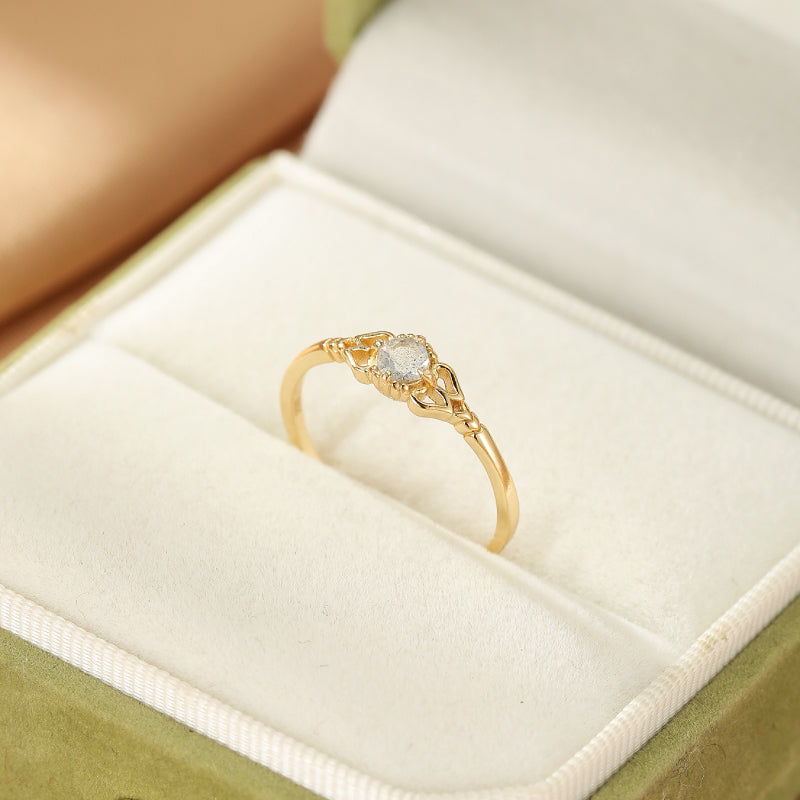 Bague fine en argent plaqué or, sertie d'une pierre de labradorite centrale et ornée de motifs délicats sur l'anneau.