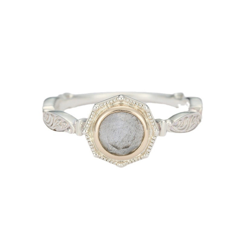 Bague élégante en argent plaqué or, sertie d'une pierre de labradorite grise aux reflets subtils, avec une monture octogonale ornée de motifs floraux sur le corps de la bague.