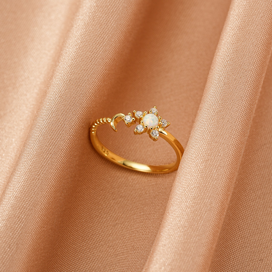 Bague en argent plaqué or avec une opale centrale et des zircons cubiques formant une étoile et une lune.