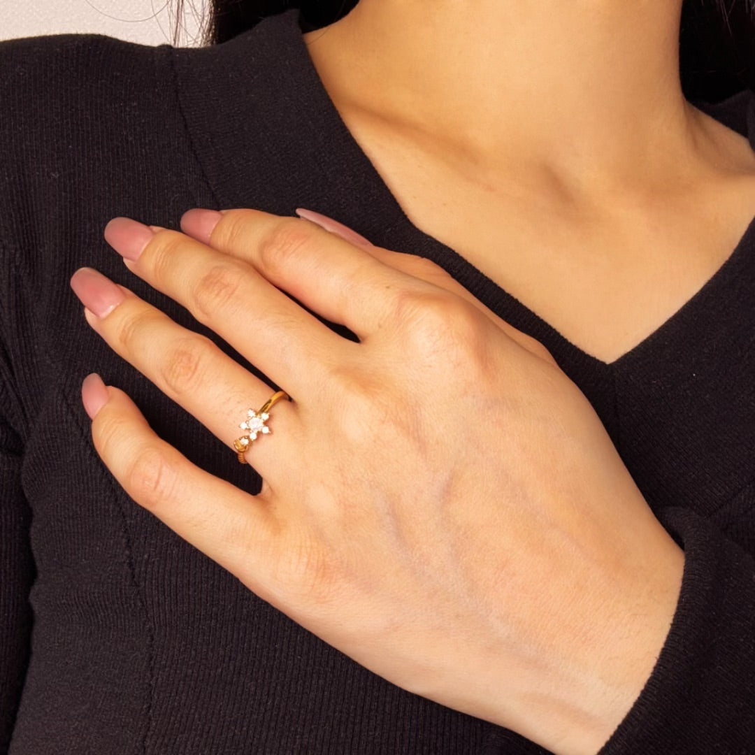 Bague fine en argent avec une opale en forme d'étoile, portée à l'annulaire d'une main aux ongles vernis en rose pâle.
