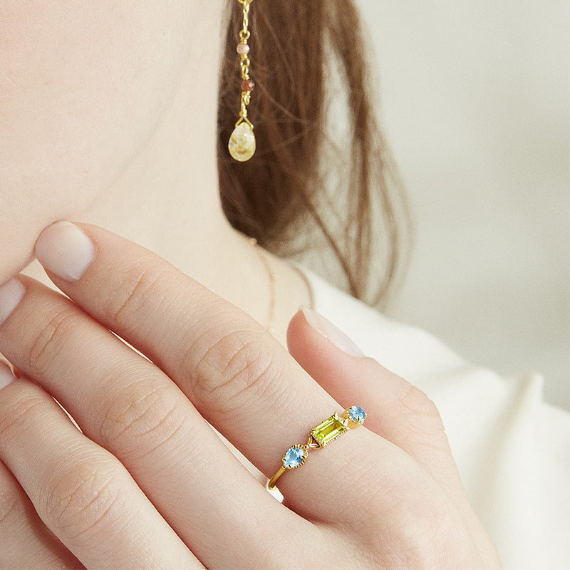 Bague en argent plaqué or avec une pierre centrale rectangulaire péridot vert et deux petites pierres bleues rondes de topaze de chaque côté.