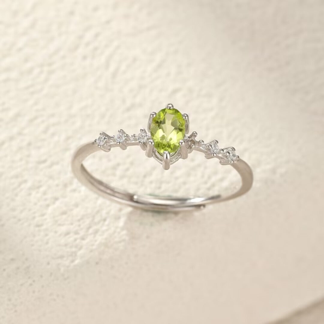 Bague ajustable en argent 925 ornée d'une pierre centrale péridot ovale et de petites pierres d'oxydes de zirconium sur le corps de la bague.