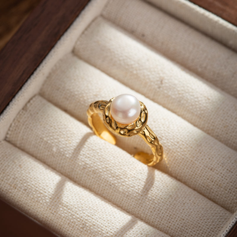 Bague en argent plaqué or sertie d'une perle blanche naturelle, posée dans un écrin de bijouterie.