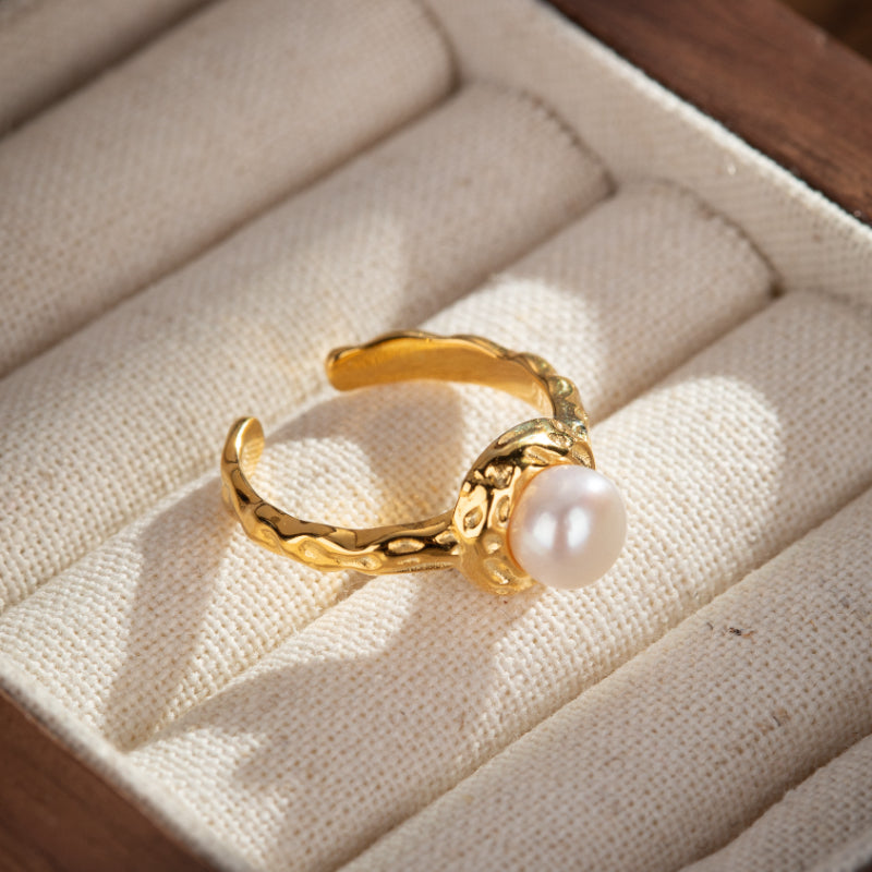 Bague ajustée en argent plaqué or avec une perle rose pâle et une texture martelée sur le corps de la bague.