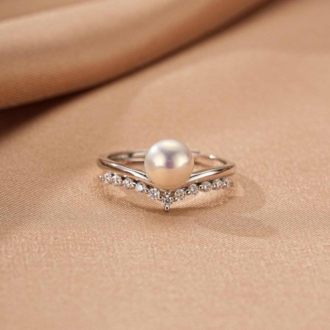 Bague empilable en argent 925 avec une perle blanche centrale et une rangée de zircons cubiques sur une chaîne en V.