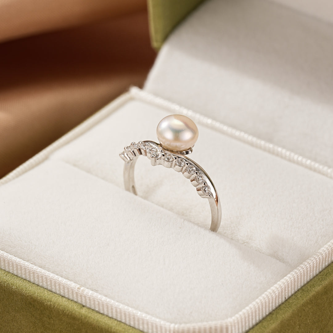 Bague élégante en argent 925 ornée d'une perle blanche et de petites pierres scintillantes, présentée dans un écrin vert.
