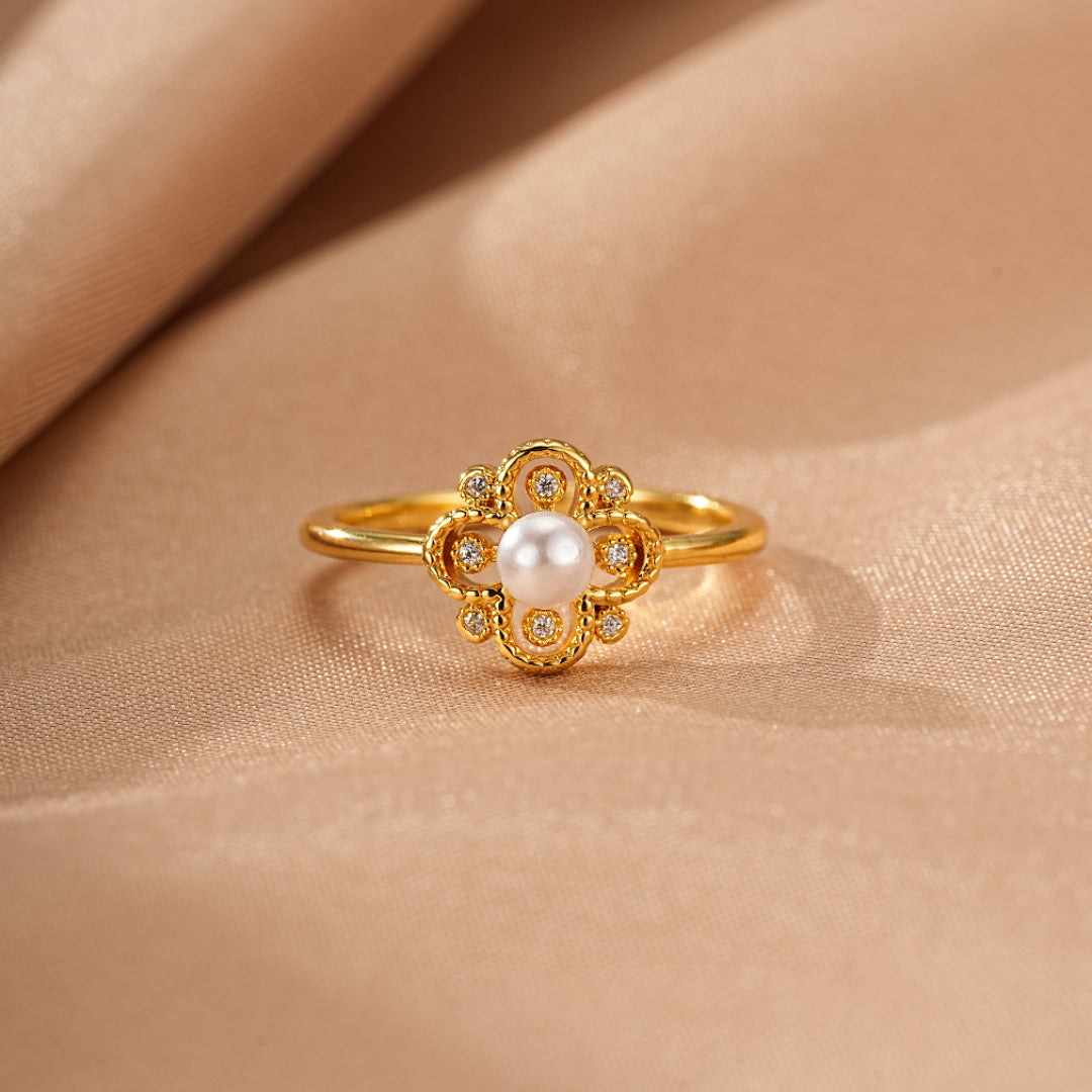 Bague en or jaune sertie d'une perle blanche et de petits diamants, avec un design floral en forme de trèfle.