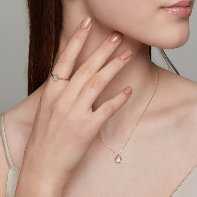 Bague en argent plaqué or sertie d'une pierre de lune ovale, portée par une femme.