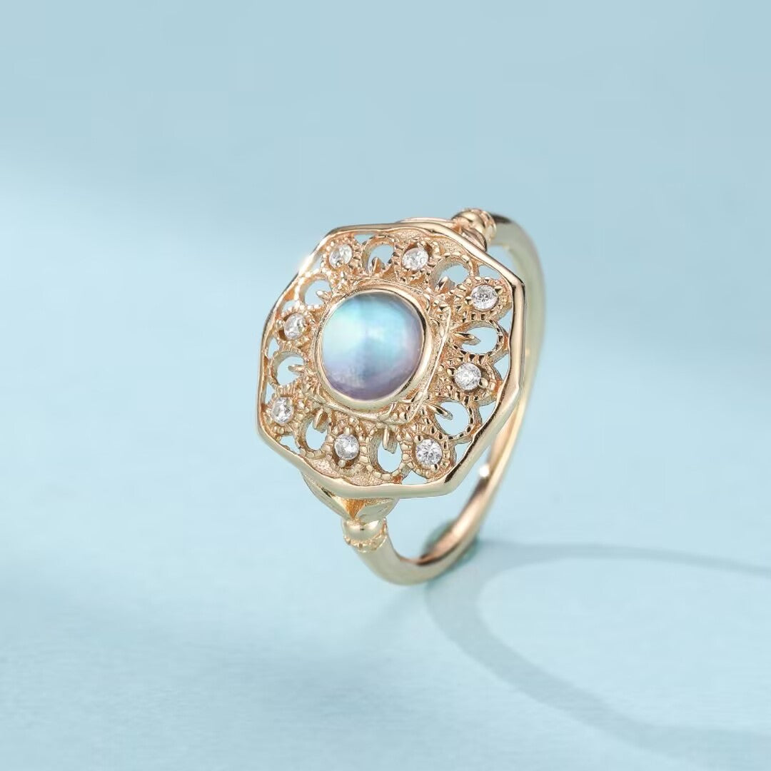 Bague en argent plaqué or avec une pierre de lune bleue et des zircons incrustés dans un design antique octogonal détaillé.