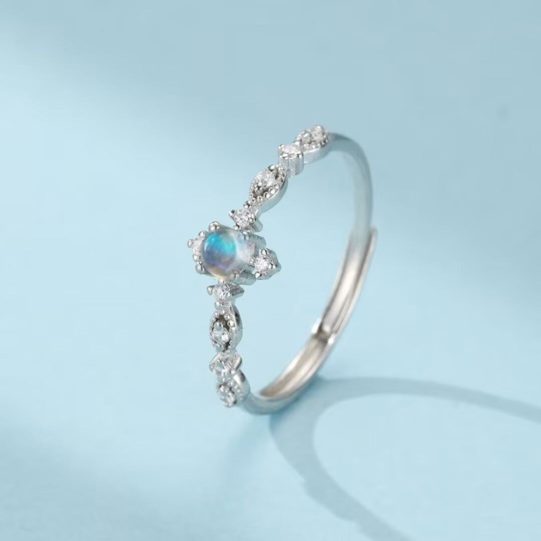 Bague en argent avec une pierre de lune bleutée et des petits cristaux incrustés sur le côté
