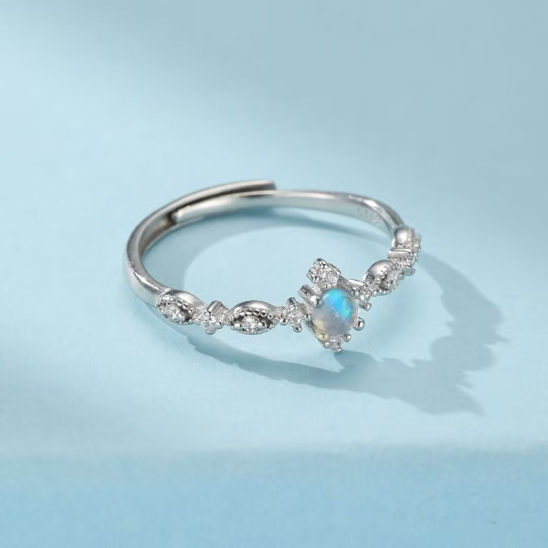 Bague ajustable en argent ornée d'une pierre de lune bleue et de petits cristaux scintillants, design délicat.