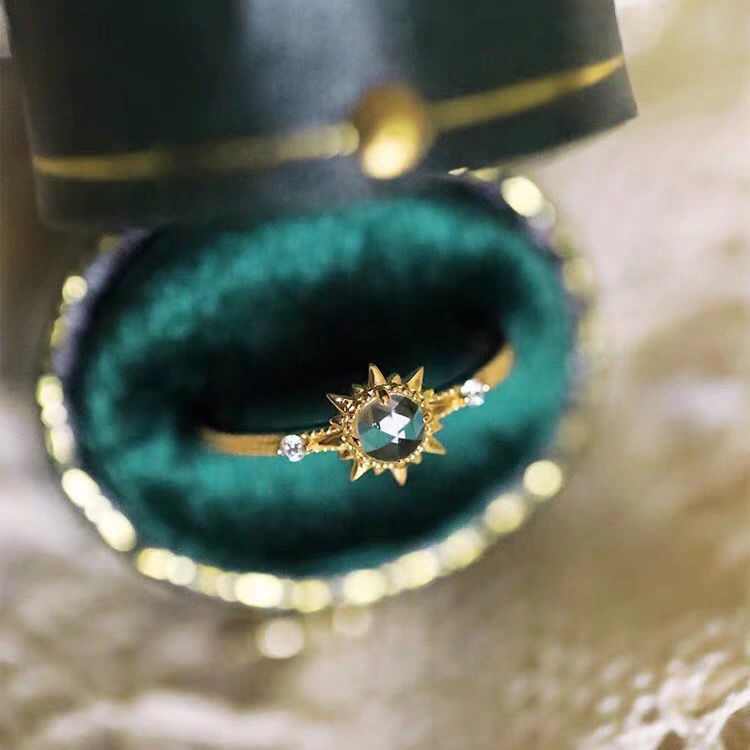 Bague en argent plaqué or avec un quartz clair central et deux petits diamants, sertie sur un anneau fin orné d'une monture en étoile.
