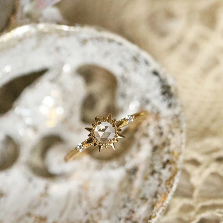 Bague en argent plaqué or ornée d'un quartz clair taille rose en forme de soleil, avec de petites pierres sur l'anneau.