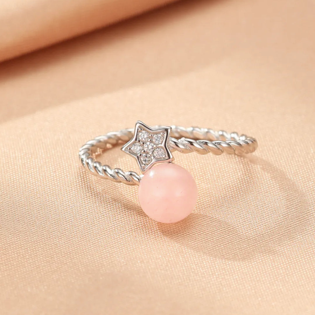 Bague en argent avec une perle rose et un motif d'étoile serti de petites pierres scintillantes.