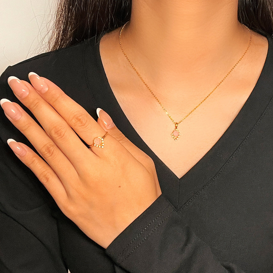 Bague en argent plaqué or 9K avec quartz rose en forme de goutte et petites pierres scintillantes, portée par une femme.