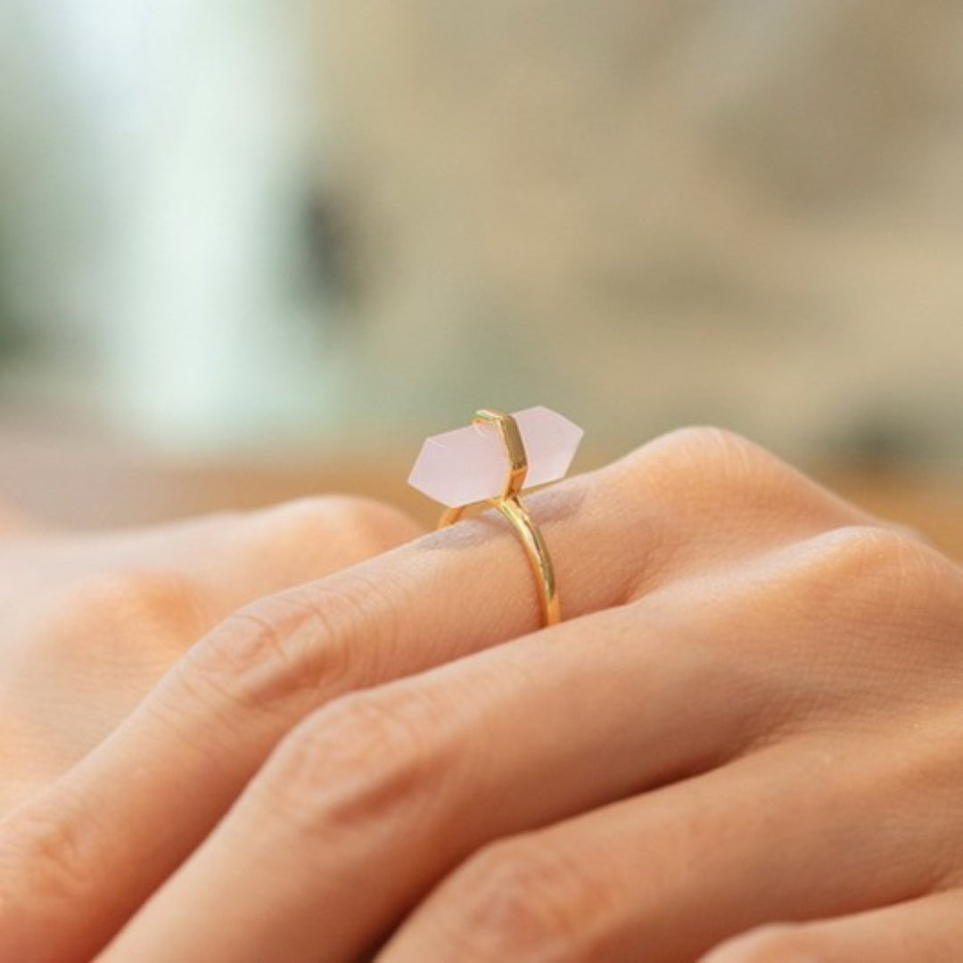 Bague en argent plaqué or 10K avec un quartz rose double pointe sur le doigt d'une femme
