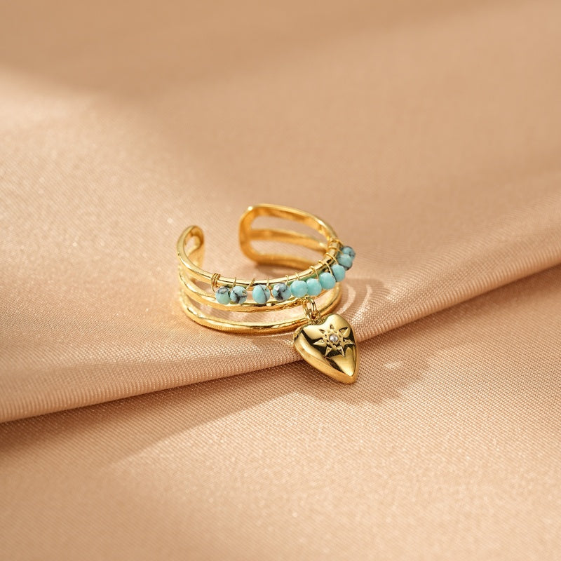 Bague ajustable dorée avec des perles turquoise et un pendentif en forme de cœur orné d'une étoile.