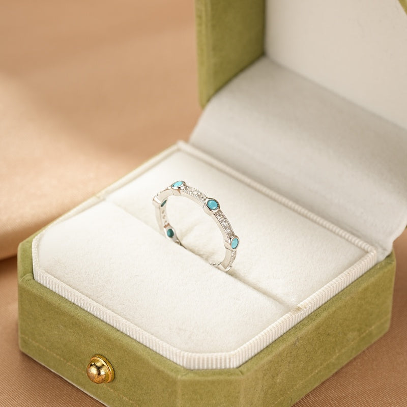 Bague en argent avec turquoise et petits diamants incrustés, présentée dans une boîte à bijoux verte. Le design de la bague est discret et élégant, rappelant l'écho des dunes.