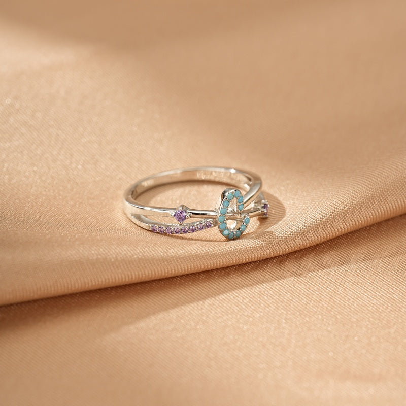 Bague en argent ornée d'une lettre C sertie de turquoise et de petites pierres violettes.