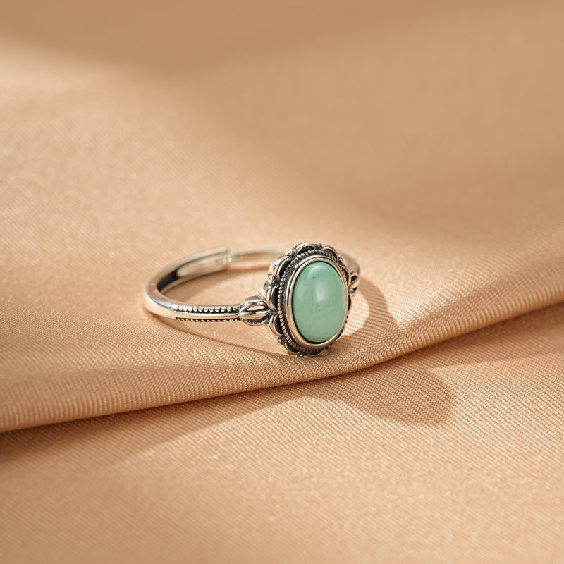 Bague ajustable en argent sterling avec une pierre turquoise ovale sertie dans un cadre orné de motifs floraux, style bohème.