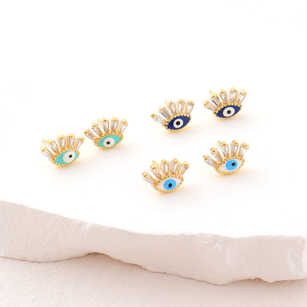 Boucles d’oreilles « Regard » en forme d'œil bleu et turquoise ornées de cristaux et montées sur un support doré.