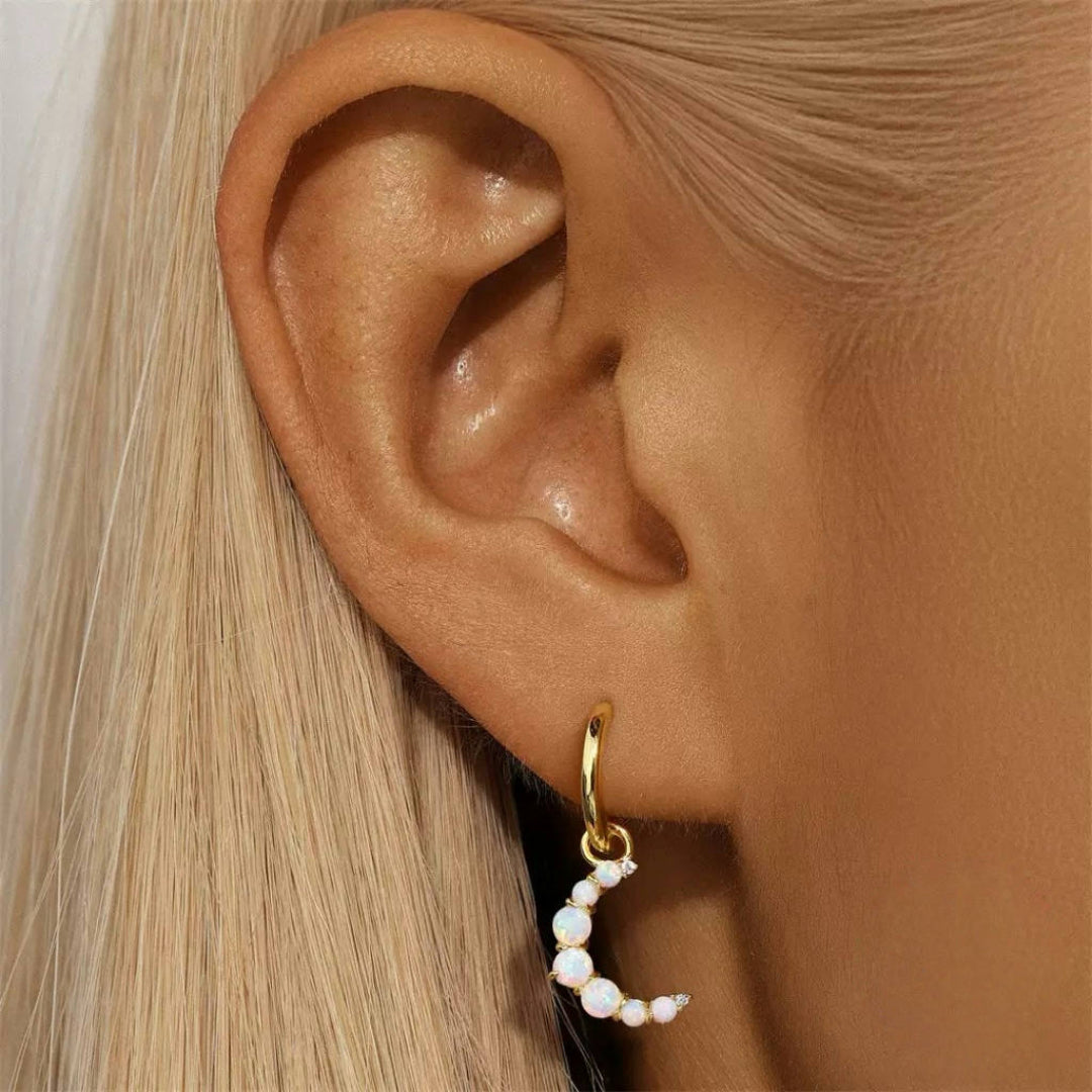 Boucle d'oreille créole en argent 925 plaqué or 18 carats avec un pendentif en forme de croissant de lune orné d'opales et de petites pierres scintillantes.
