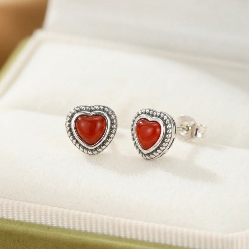 Boucles d'oreilles cœur en argent avec une belle agate rouge au centre, un bijou élégant et passionné.