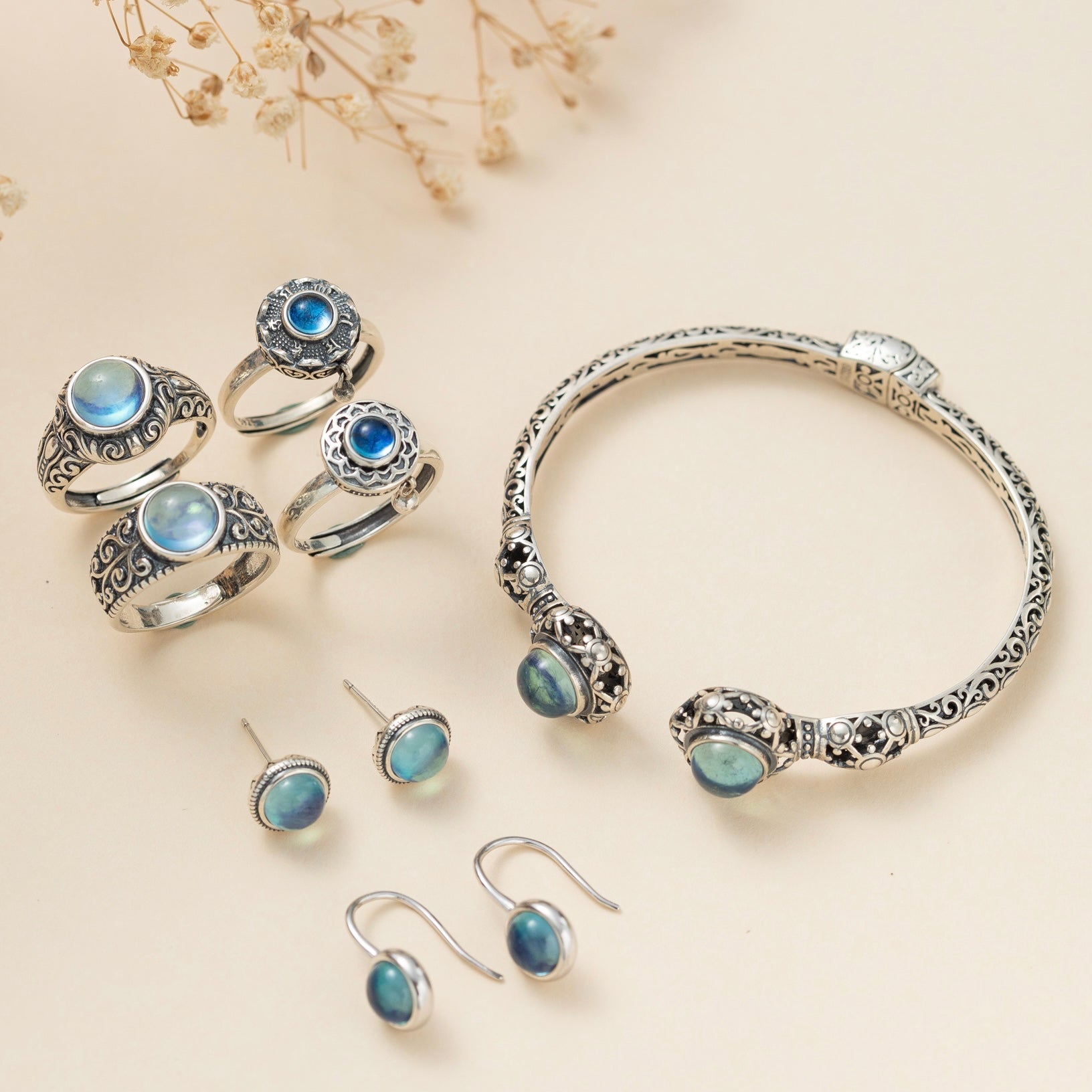 Ensemble de bijoux en argent ornés de pierres d'aigue-marine bleues et bleutées, comprenant des boucles d'oreilles, des bagues et un bracelet ouvert.