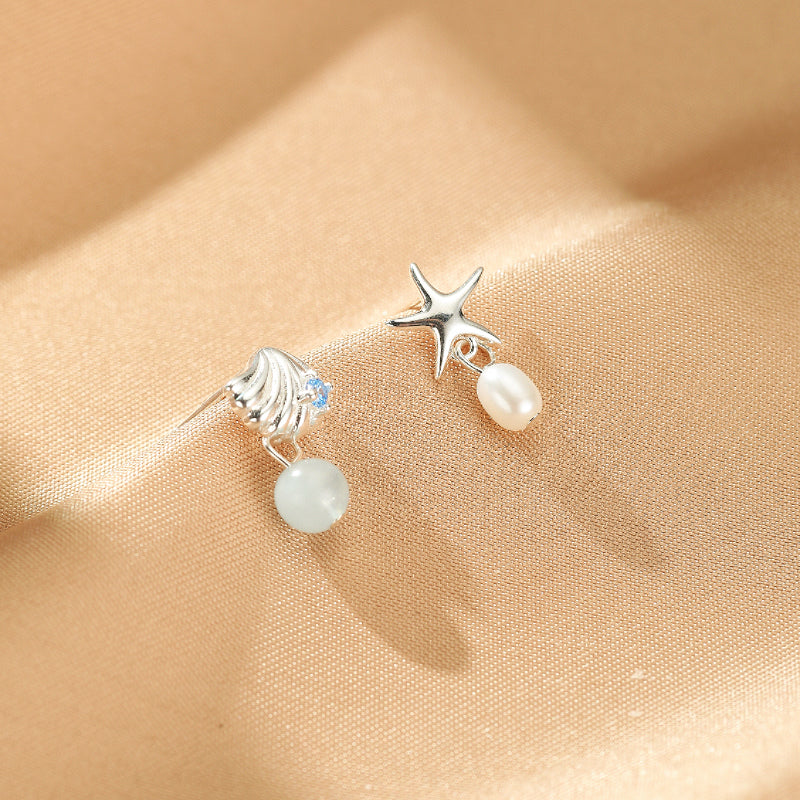 Boucles d'oreilles "Étoile de l'Océan" en argent avec une aigue-marine bleue et une perle blanche, perle blanche ressemblant à un coquillage et une étoile de mer.