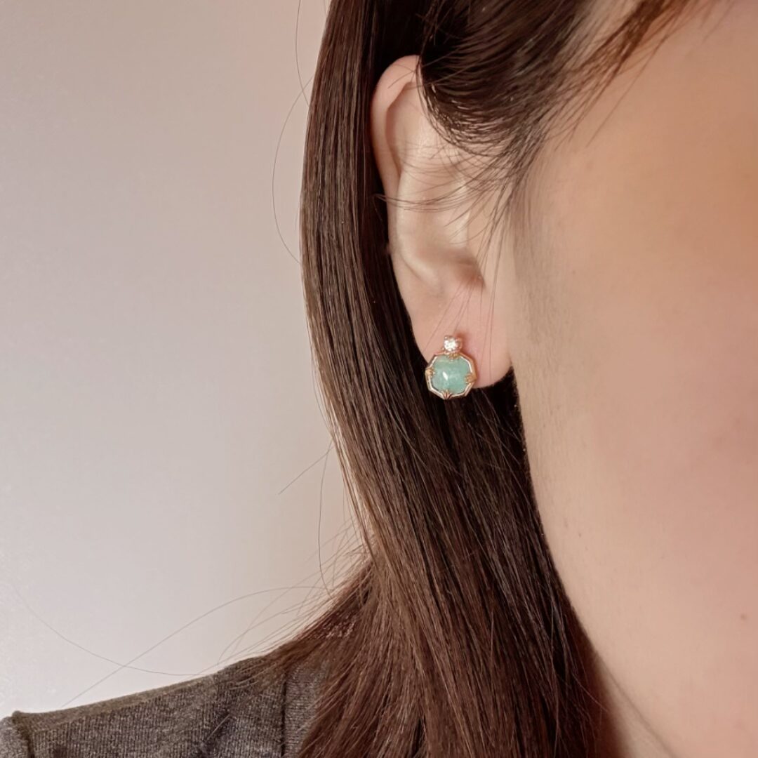 Boucles d'oreilles en argent plaqué or ornées d'une pierre centrale bleu pâle entourée de zircons scintillants, portées par une femme.