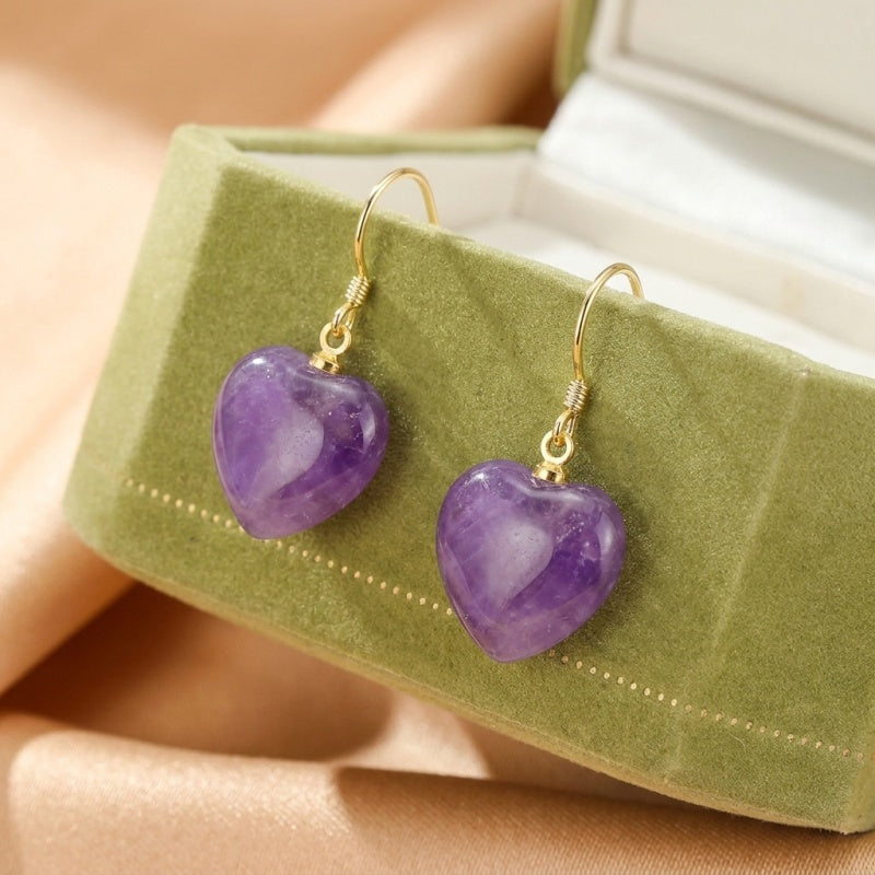 Boucles d'oreilles cœur en améthyste avec fermoir plaqué or, présentées dans une boîte à bijoux verte.