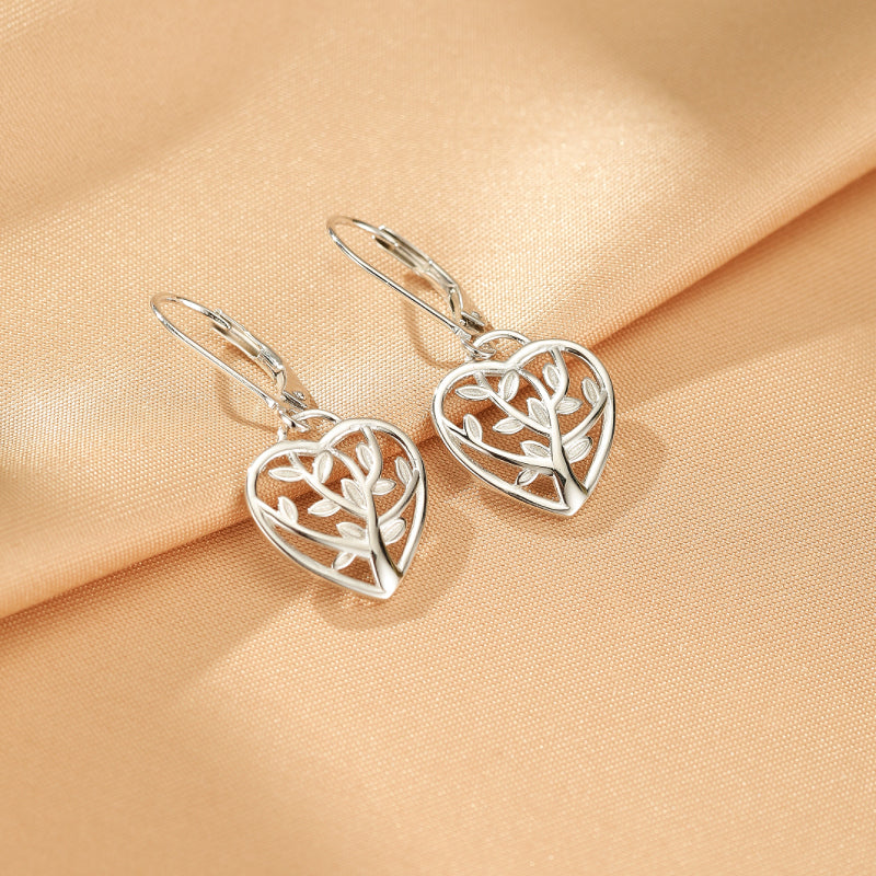 Boucles d'oreilles en argent 925 avec un motif d'arbre de vie en forme de cœur, sur un fond satiné.