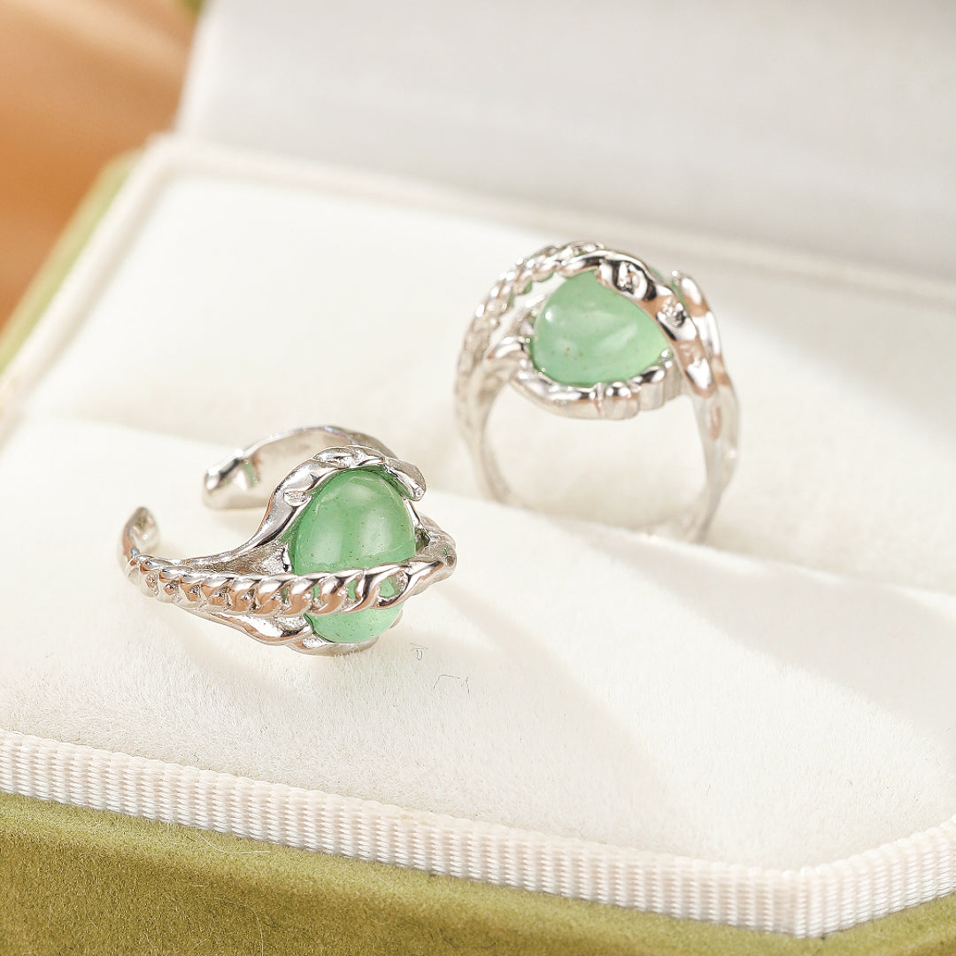 Deux bagues en argent serties d'une pierre verte d'aventurine, présentées dans un écrin vert.