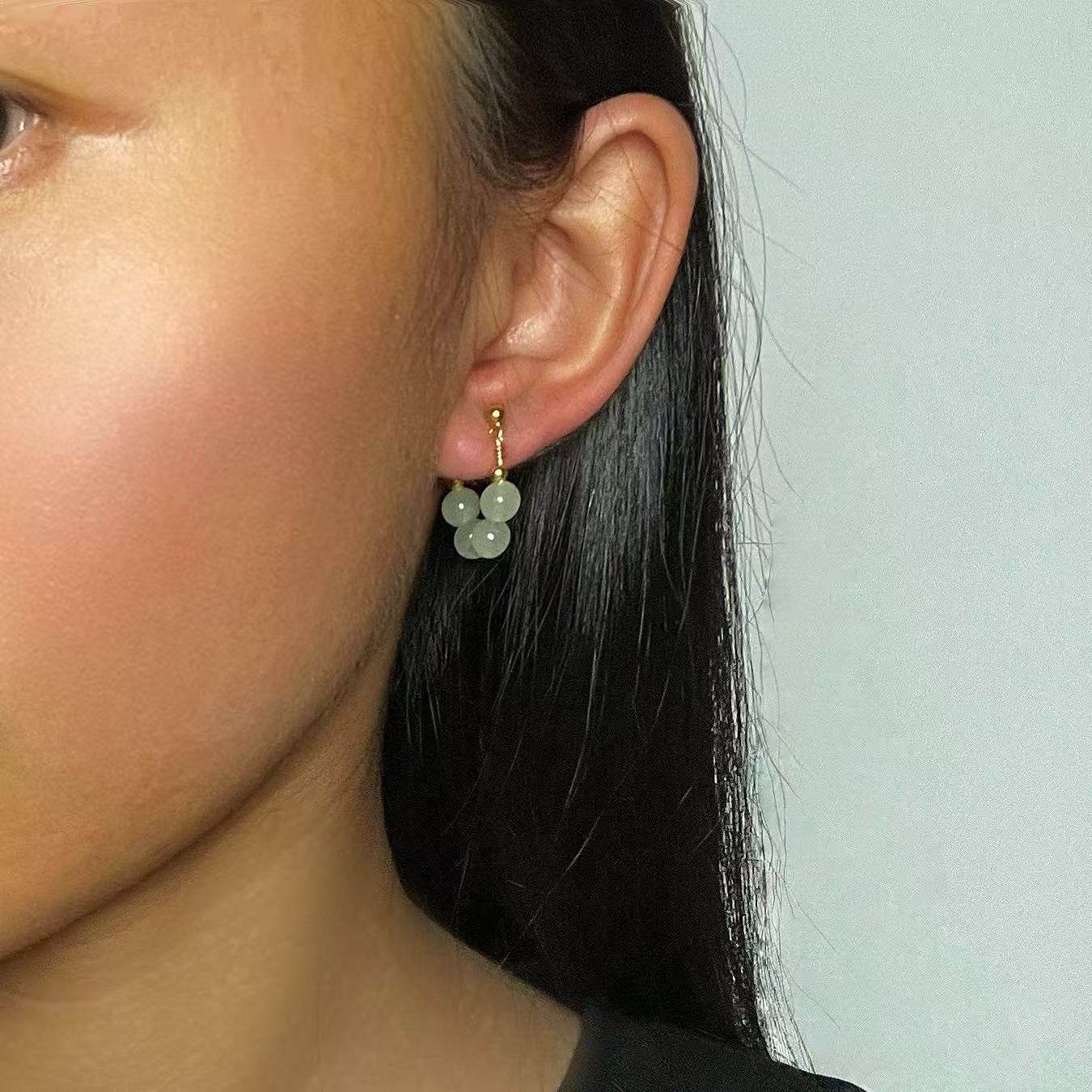 Boucles d’oreilles créoles pendantes en argent avec des grappes de perles de jade vert pâle.