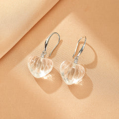 Boucles d'oreilles en argent ornées de cœurs en cristal de roche sculpté, avec de petites pierres scintillantes sur l'attache.