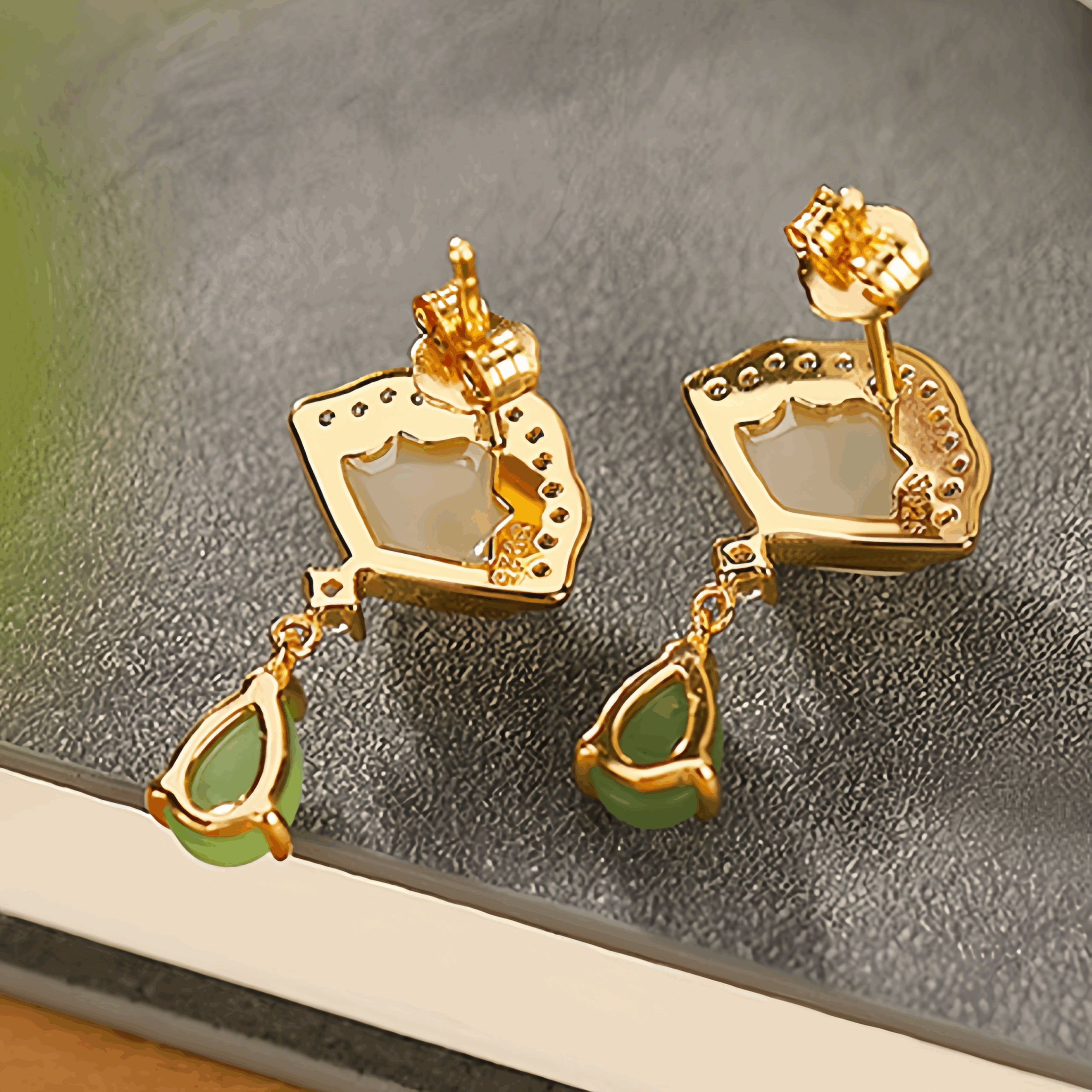 Paire de boucles d'oreilles pendantes en argent plaqué or, ornées de pierres de jade verte en forme de goutte et d'un élément central en nacre blanche incrusté de petits cristaux.